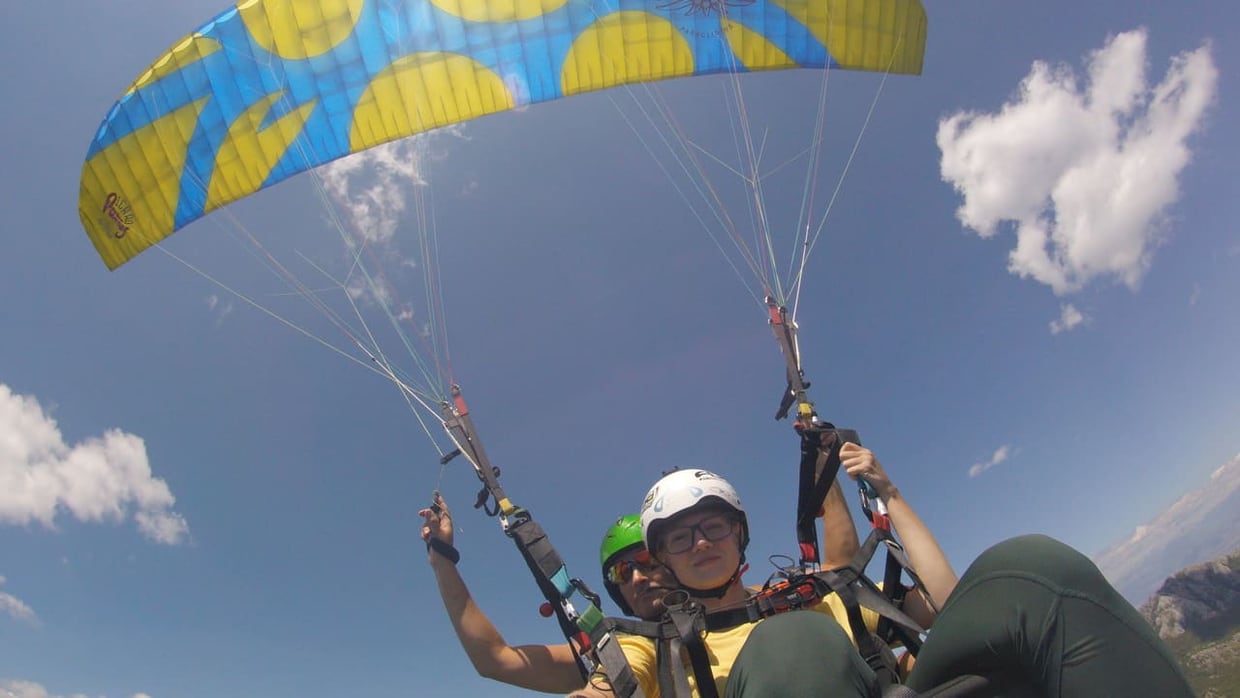 Paraglider in sustained glide above Montenegro, contrasting scenic flight with free-fall intensity